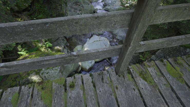 Overlooking from wooden bridge a rocky stream on a hiking trail Italian Alps region