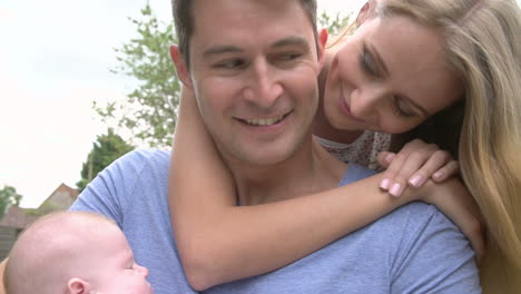 Slow-Motion-Shot-Of-Parents-Cuddling-Baby-Daughter-In-Garden