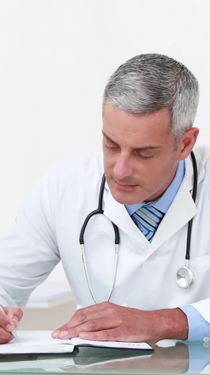 Médico trabalhando em sua mesa e sorrindo para a câmera