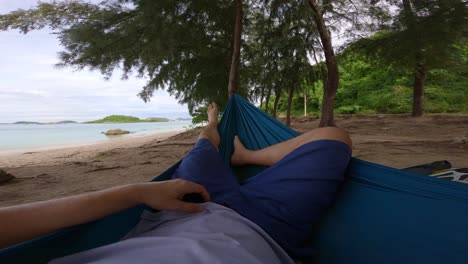 POV-Eines-Mannes,-Der-In-Seiner-Hängematte-Liegt-Und-Sich-Entspannt,-Während-Er-Sich-In-Der-Nähe-Des-Tropischen-Strandes-Ausruht