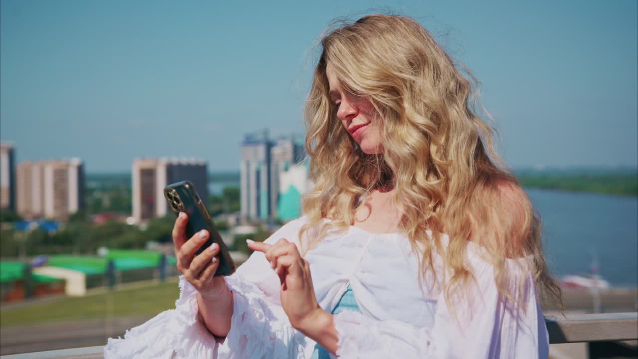Junge Frau nutzt Smartphone im Freien vor Stadtsilhouette