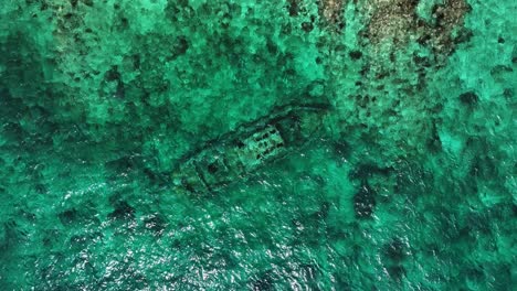 el dron está volando de arriba hacia abajo mirando un naufragio en el océano subiendo y girando en curacao imágenes aéreas 4k