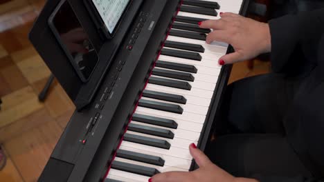 person playing a digital piano with sheet music displayed on a tablet