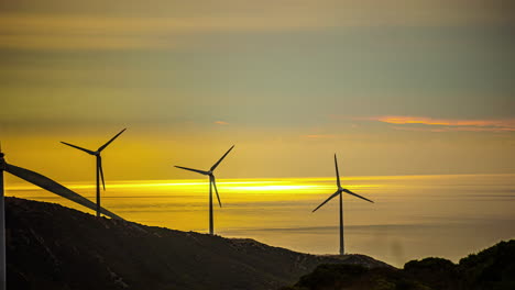 Zeitraffer-Der-Produktion-Sauberer-Energie-Auf-Grünen-Feldern-Einer-Windkraftanlage-In-Der-Nähe-Des-Meeres-Bei-Sonnenuntergang