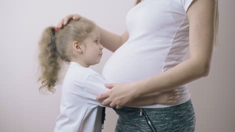 Hübsches-Mädchen-Umarmt-Schwangere-Mama-Mit-Großem-Bauch-Zu-Hause