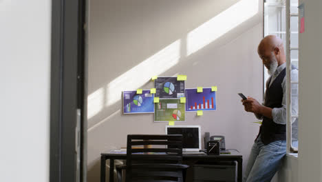 hombre de negocios usando teléfono móvil cerca de la ventana 4k