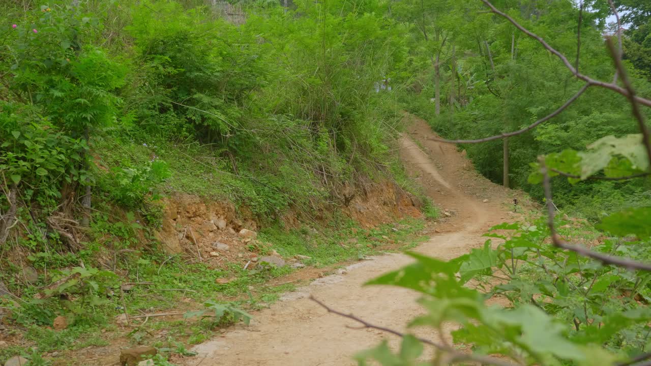 joven asiático local montando una motocicleta a través de caminos rurales, sudeste asiático