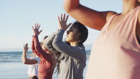 group of diverse female friends practicing yoga at the beach