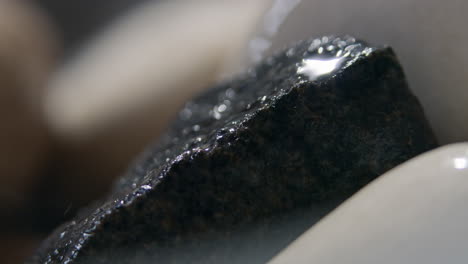 throwing water on a stack of hot stones in the sauna stove, slow motion extreme close up of water splashing and evaporating into steam, heating the sauna