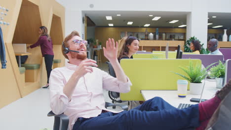 businessman wearing headset playing with stress ball talking to caller in customer services centre