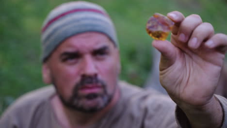man holding amber gemstone in nature