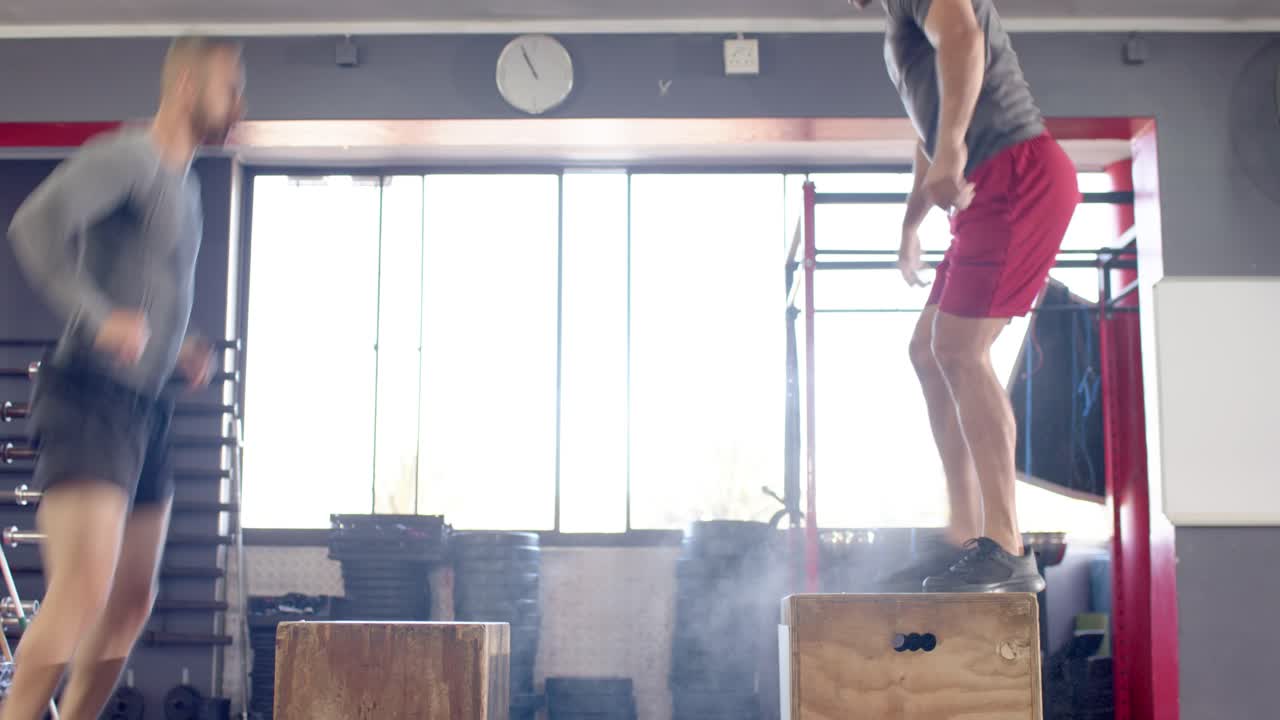 Diverse male partners squatting swinging arms exploding onto wooden boxes with chalk puffs