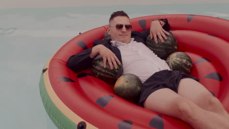 man relaxing on a watermelon-shaped pool float