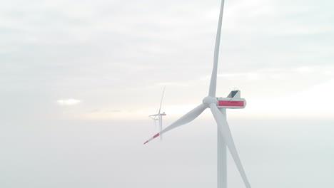 Toma-Aérea-De-Turbinas-De-Molinos-De-Viento-Sobre-Una-Capa-De-Niebla-Densa,-Que-Produce-Energía-Verde-Y-Limpia-Recortada