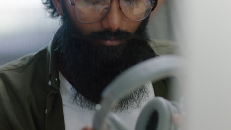 close-up-portrait-young-indian-businessman-using-computer-brainstorming-browsing-online-research-ideas-for-startup-company-project-networking-reading-email-listening-to-music-in-busy-modern-office