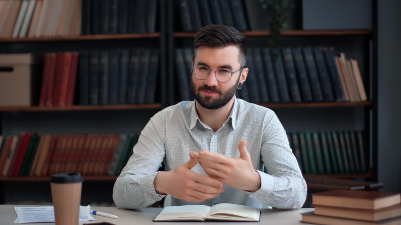 Hispanic male blogger shooting video talking explaining business education news at library desk