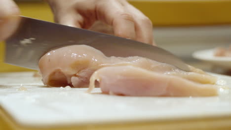 close up cutting raw chicken with a knife in the kitchen