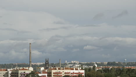 nubes blancas que se mueven sobre edificios urbanos y chimeneas de fábricas