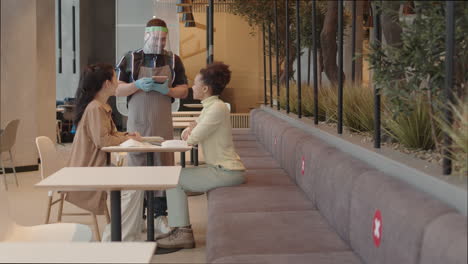 waiter taking order from young women