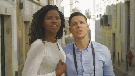 joyful multiracial couple looking up outdoor.