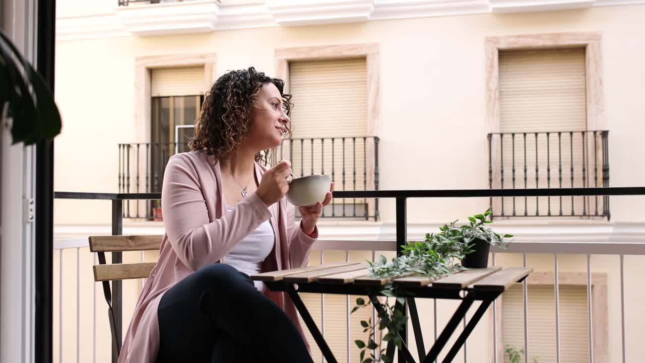 Woman enjoying breakfast on urban balcony