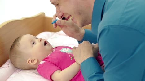 CU-Young-father-plays-with-little-sweet-baby-who-lies-on-a-changing-table