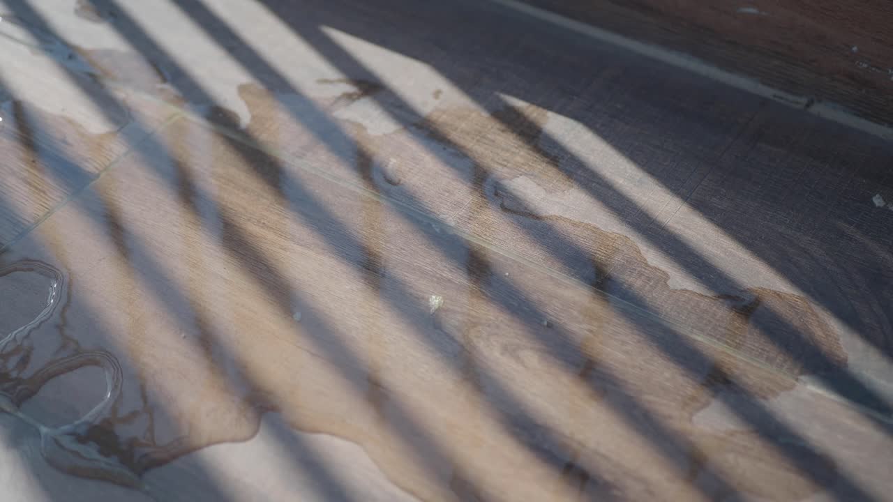 Water Spill and Striped Shadows on a Wood Floor