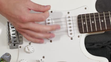 a medium shot of a man playing guitar solos, chords and rhythm with bass in a studio focussing on the hands