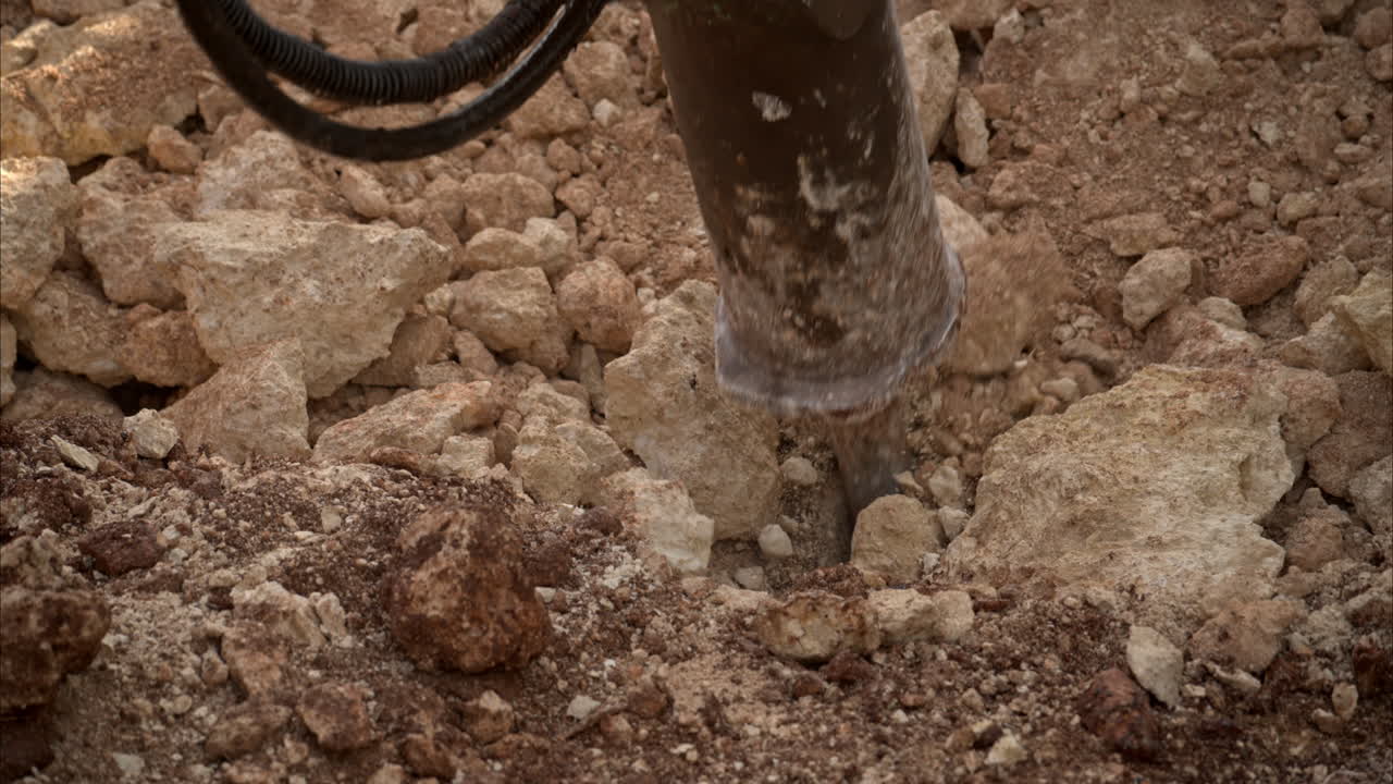 Slow motion close up of an hydraulic hammer shoveling and pushing rocks in a construction site