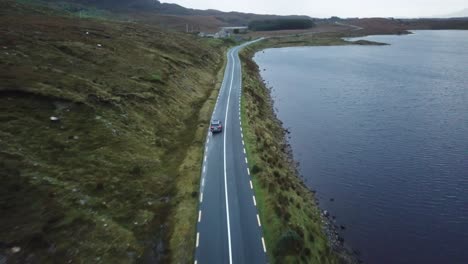 aerial scenic view of a car driving in connemara, ireland, near the ocean