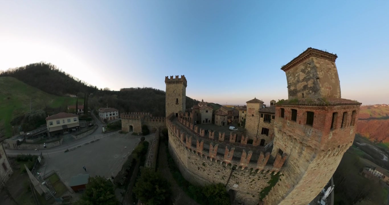 Rocca Viscontea di Castell’Arquato, che rivela torri in pietra, bastioni e il vicino villaggio al tramonto. Avanzamento aereo