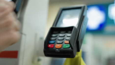 a close-up of a hand wearing a beaded bracelet making a payment with a card.the background is blurred, emphasizing the payment process