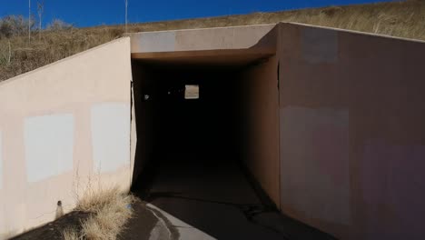 a drone shot emerging out of a tunnel along a bike path