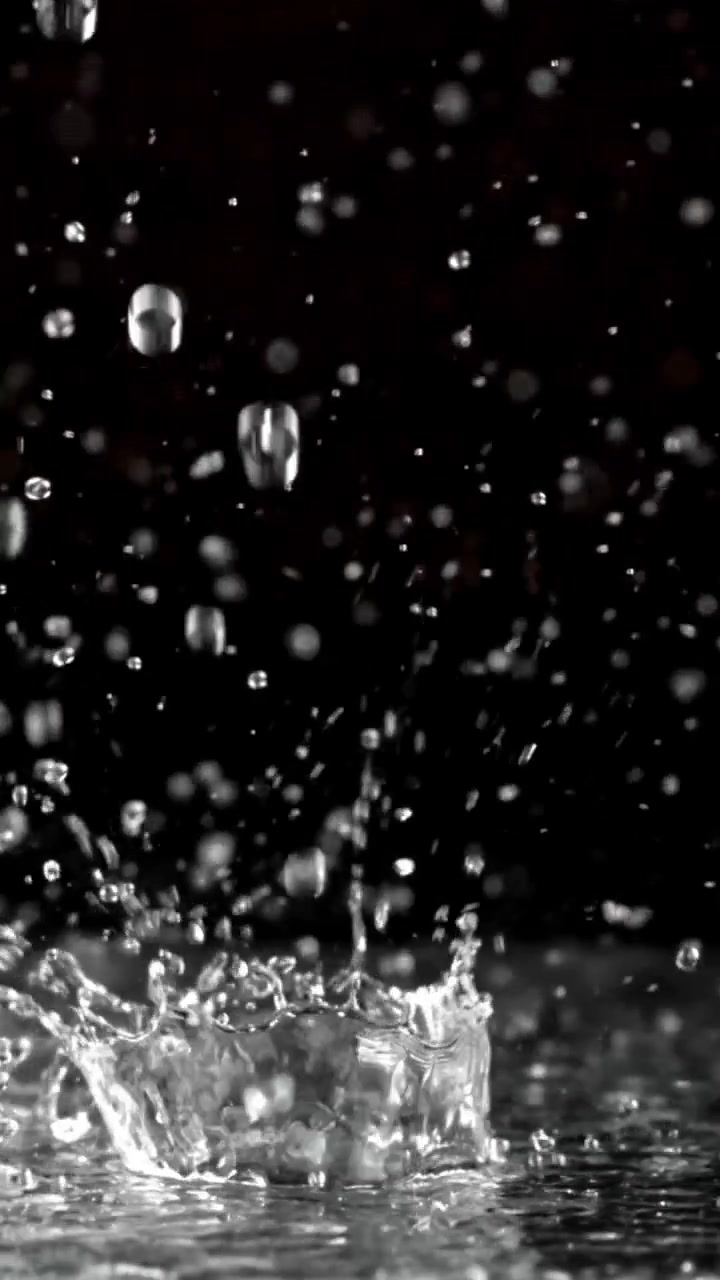 Slow Motion Water Droplets Falling and Splashing on a Dark Background