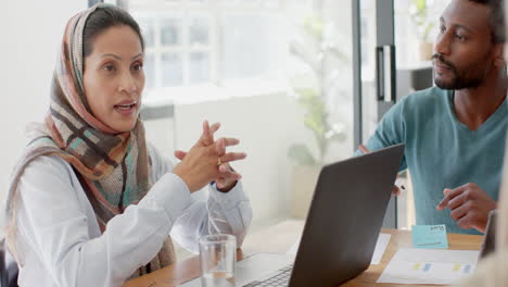 Busy-diverse-business-people-discussing-work-at-table-with-laptop-in-slow-motion