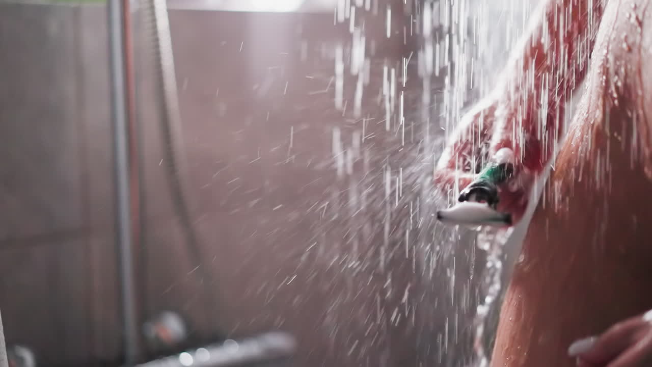 mujer lava la navaja de afeitar de pie en el flujo de la ducha de cerca. atractiva dama desnuda con piel lisa limpia la cuchilla después de afeitarse en el baño. lavado del cuerpo