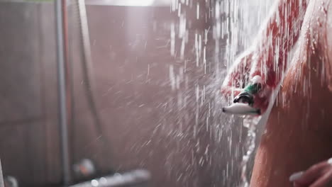 mujer lava la navaja de afeitar de pie en el flujo de la ducha de cerca. atractiva dama desnuda con piel lisa limpia la cuchilla después de afeitarse en el baño. lavado del cuerpo