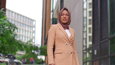 Portrait-Of-Smiling-Muslim-Businesswoman-Wearing-Hijab-With-Business-Suit-Going-To-Work-Standing-Outside-Modern-Office-Buildings-1