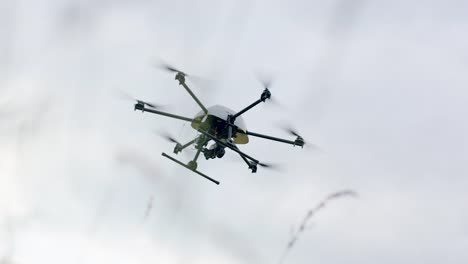 Dron-De-Cámara-Profesional,-Hexacóptero,-Se-Cierne-En-El-Cielo,-ángulo-Bajo-A-Través-Del-Prado