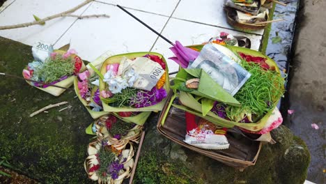 Ofrendas-Exhibidas-En-El-Suelo-Ritual-Para-Atraer-Dinero-Y-Buena-Suerte-En-La-Religión-Hinduista-Balinesa,-Flores,-Hojas-De-Coco-Y-Billetes-En-Efectivo