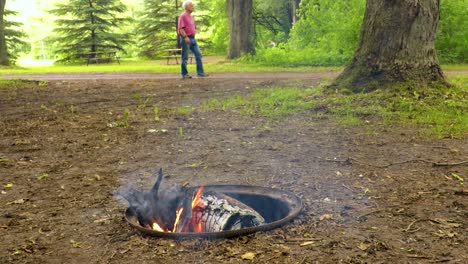 El-Hombre-Camina-De-Izquierda-A-Derecha-En-El-Fondo-De-Un-Incendio-En-Un-Campamento