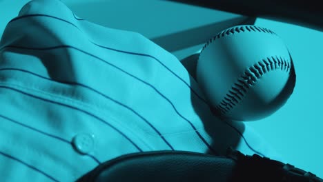 close up studio baseball still life with ball catchers mitt and team jersey with blue lighting