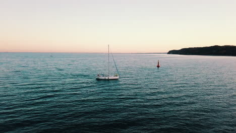 drone flying above the yacht sailing into the bay at the sunset