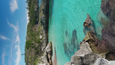 Aerial:-secluded-bay-and-turquoise-coral-sea,-Maré-Island-New-Caledonia,-vertical-format