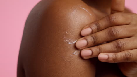 woman applying lotion to shoulder