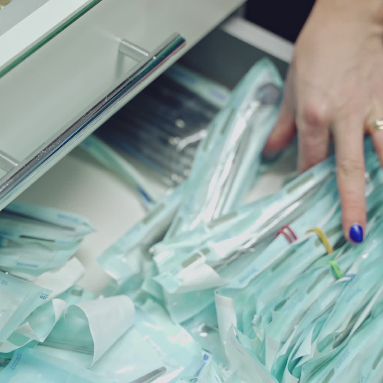 Detail of hand taking out sterile dental tools in medical clinic. Hands in latex gloves takes instruments from drawer. Dentist concept. Close-up