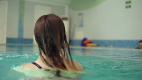 Close-up-of-a-young-wet-woman-swimming-with-his-little-blonde-son.-Whirling-above-the-water,-splashing.-Have-a-happy-time-together.-Parenthood.-Indoors-swimming-pool