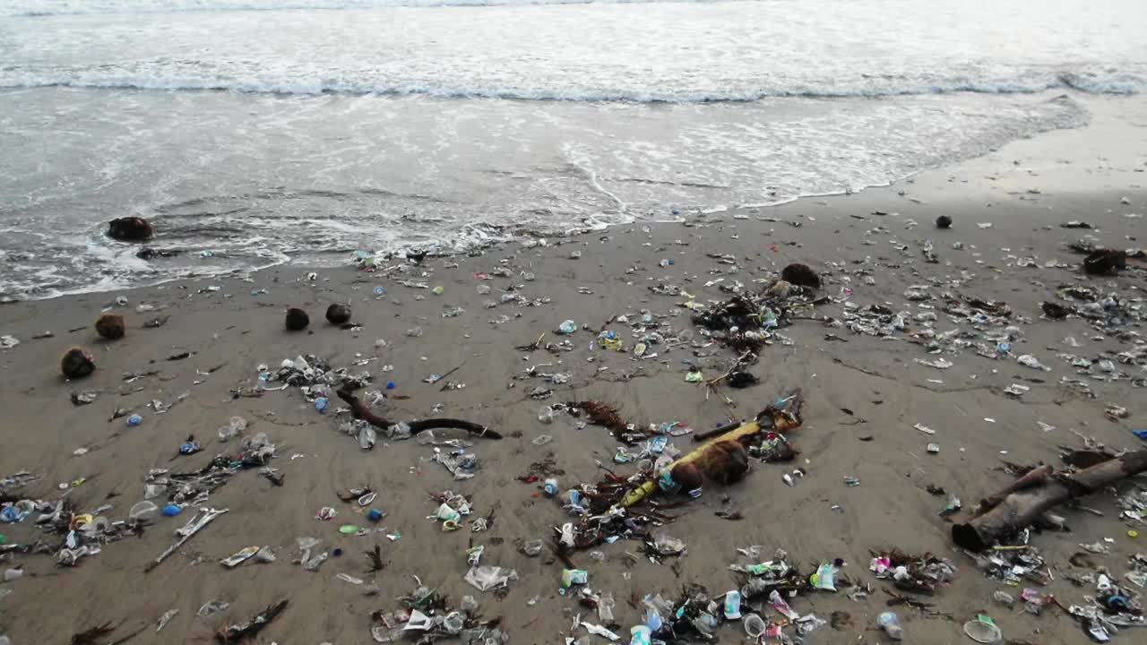 Slow motion shot as waves washing out trash from the ocean, garbage on the beach