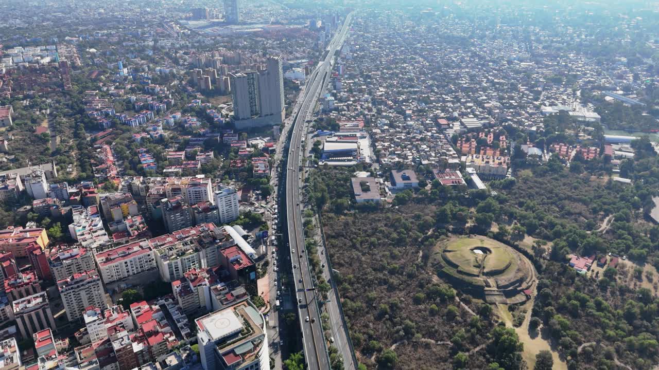 Modern Meksiko Şehri ile çevrili Cuicuilco Piramidi'ni görüntüleyen drone çekimi