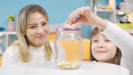 Cute-and-cheerful-little-girl-peeks-into-her-piggy-bank,-saves-money.